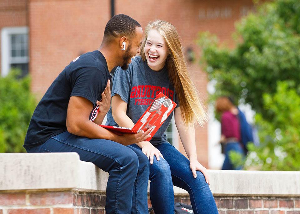 students resting on wall in lower quad